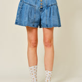 Denim shorts worn by a person on a plain background