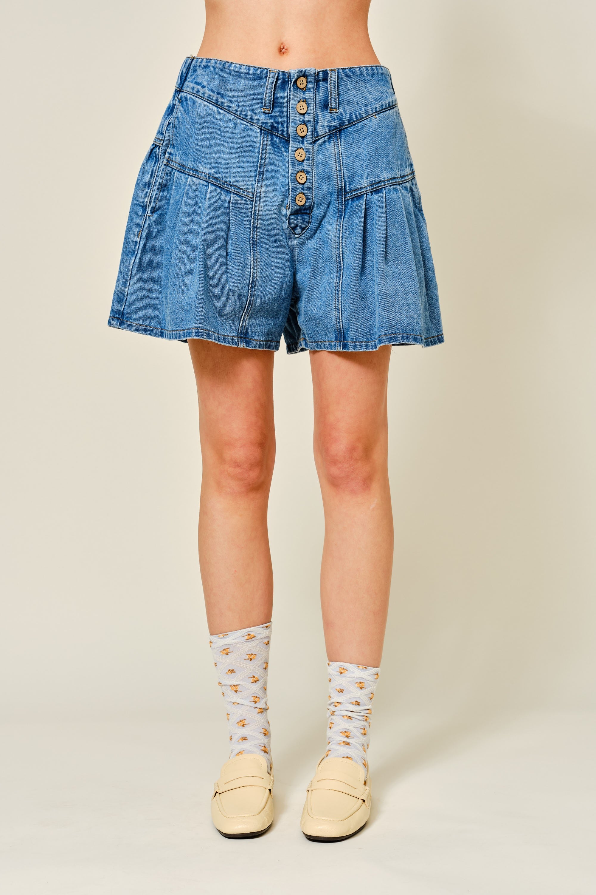 Denim shorts worn by a person on a plain background