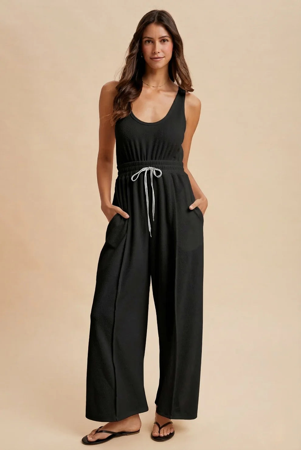 Woman wearing a black jumpsuit on a beige background