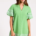 Woman wearing a green dress with white embroidery on a white background