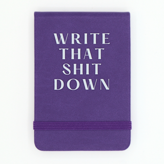 Purple notebook with white text 'WRITE THAT SHIT DOWN' on a white background