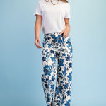 Woman wearing a white t-shirt and blue floral pants on a light blue background