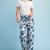 Woman wearing a white t-shirt and blue floral pants on a light blue background