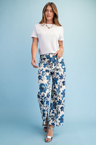 Woman wearing a white t-shirt and blue floral pants on a light blue background