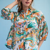 Woman wearing a colorful patterned blouse against a blue background