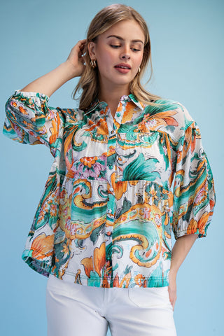 Woman wearing a colorful patterned blouse against a blue background