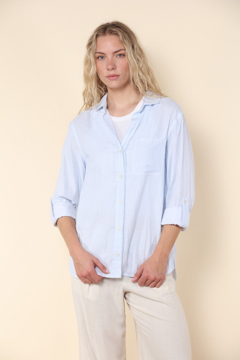 Woman wearing a light blue shirt and beige pants against a beige background