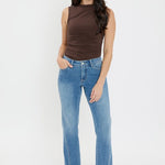 Woman wearing a brown sleeveless top and blue jeans on a white background