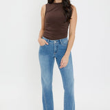 Woman wearing a brown sleeveless top and blue jeans on a white background