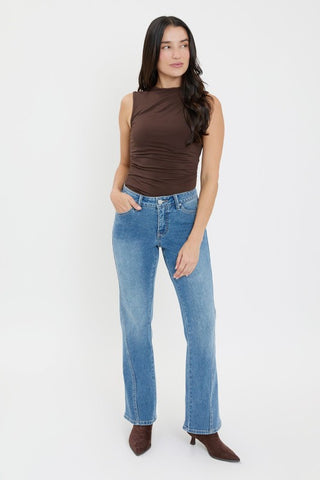 Woman wearing a brown sleeveless top and blue jeans on a white background
