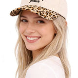 Woman wearing a beige cap with leopard print brim and text, on a white background