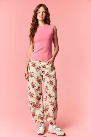 Woman wearing a pink sleeveless top and floral pants on a pink background