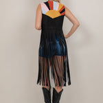 Woman wearing a colorful sleeveless dress with fringe details on a plain background