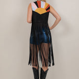 Woman wearing a colorful sleeveless dress with fringe details on a plain background