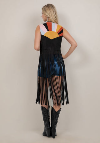 Woman wearing a colorful sleeveless dress with fringe details on a plain background