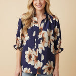 Woman wearing a floral blouse with rolled-up sleeves on a beige background