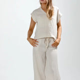 Woman wearing a beige sleeveless top and wide-leg pants on a white background