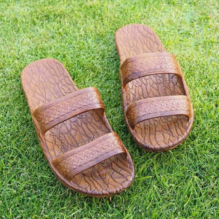Pair of brown sandals with textured straps on a grass background