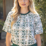 Woman wearing a lace top with green trim outdoors