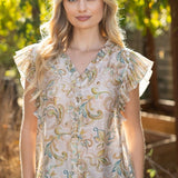 Woman wearing a floral blouse with ruffled sleeves outdoors