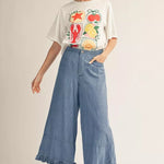Woman wearing a graphic t-shirt and wide-leg jeans on a plain background