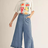 Woman wearing a graphic t-shirt and wide-leg jeans on a plain background