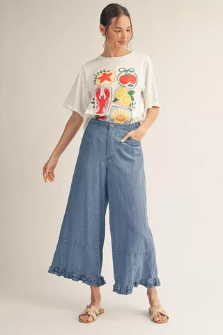 Woman wearing a graphic t-shirt and wide-leg jeans on a plain background