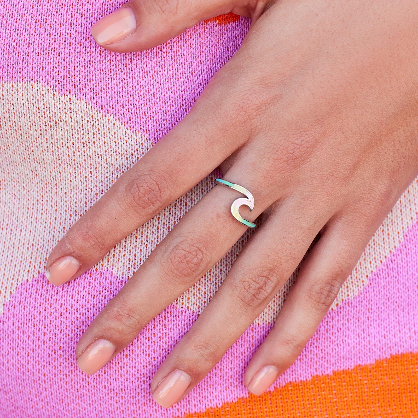 Hand wearing a green ring on a colorful fabric background