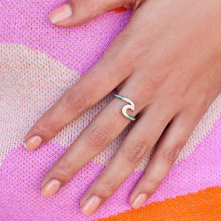 Hand wearing a green ring on a colorful fabric background