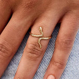 Gold snake-shaped ring on a person's finger with a denim background