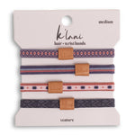 Set of three patterned hair or wrist bands with brown leather ends on a 'ká lani' branded card.