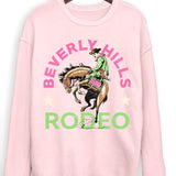 Pink sweatshirt with 'Beverly Hills Rodeo' graphic on a hanger against a white background