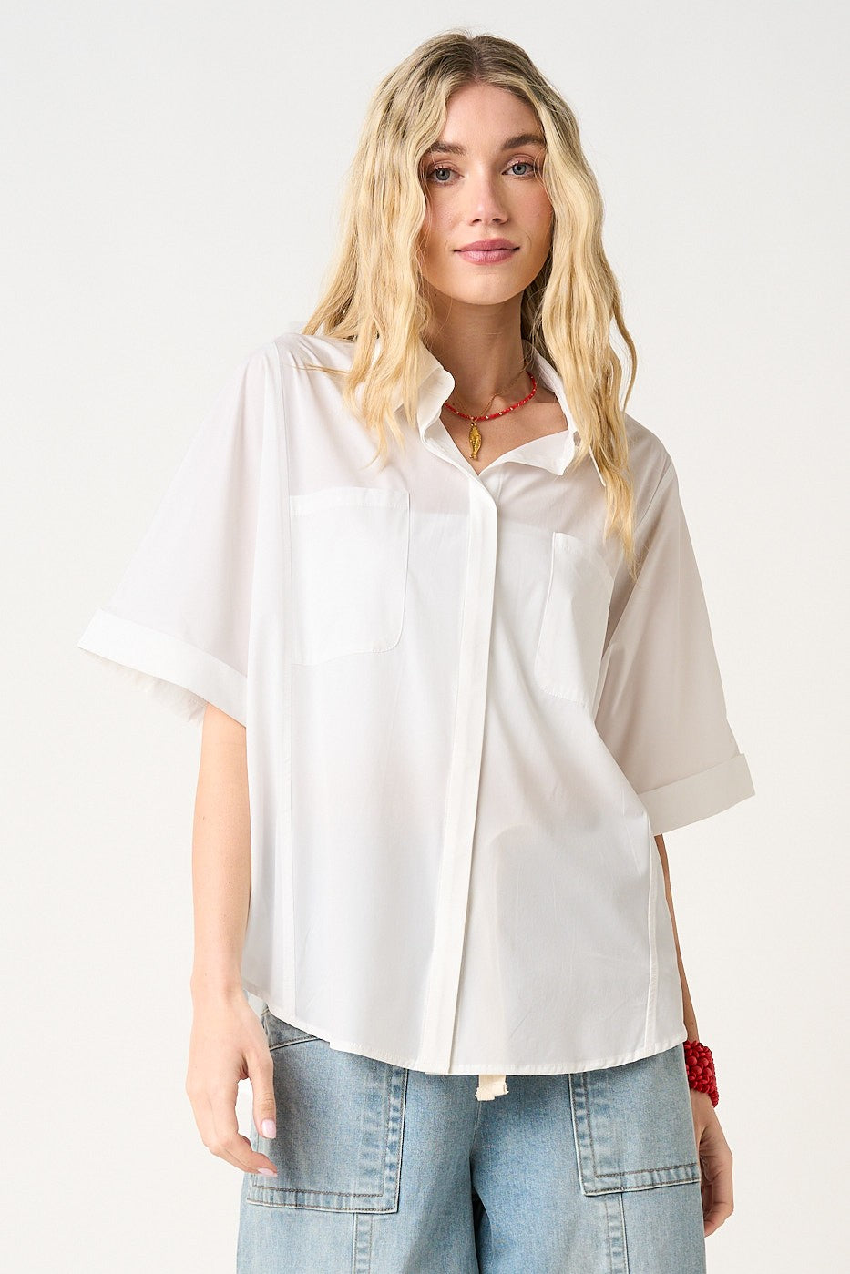 Woman wearing a white oversized shirt and blue jeans on a white background