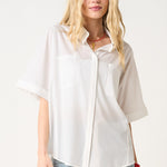 Woman wearing a white oversized shirt and blue jeans on a white background