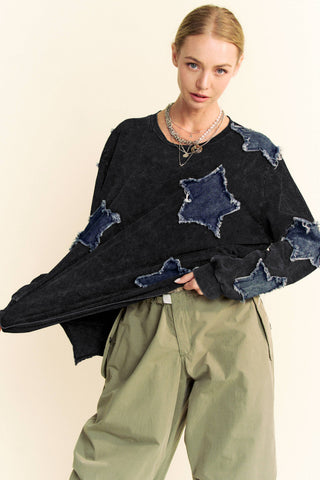Person wearing a black sweater with star-shaped cutouts and green pants on a beige background