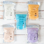Assorted packages of Simplified body scrubs on a wooden surface