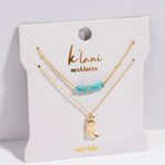 Gold necklace with turquoise beads and boot charm on a 'klambi necklaces' card.