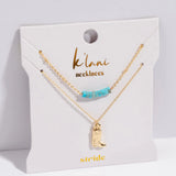Gold necklace with turquoise beads and boot charm on a 'klambi necklaces' card.