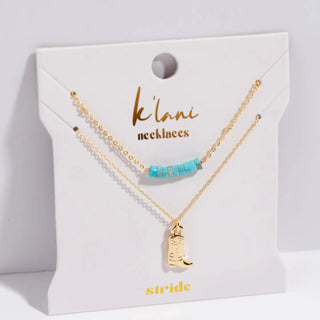 Gold necklace with turquoise beads and boot charm on a 'klambi necklaces' card.
