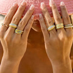 Close-up of two hands with multiple rings on a blurred background