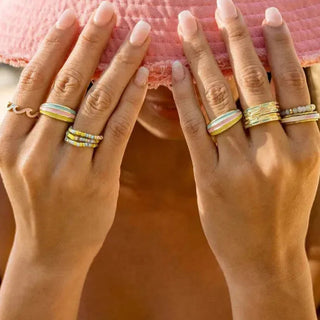 Close-up of two hands with multiple rings on a blurred background