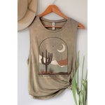 Beige tank top with desert graphic and text on a hanger against a white wall.