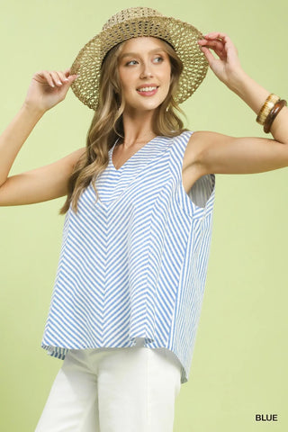 Woman wearing a straw hat and blue and white striped sleeveless top on a light green background