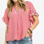 Woman wearing a red and white checkered blouse with denim shorts on a white background