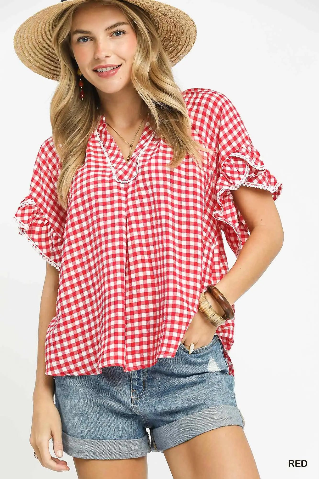 Woman wearing a red and white checkered blouse with denim shorts on a white background