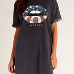 Woman wearing a dark gray t-shirt with a graphic design and text on a plain background