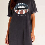 Woman wearing a dark gray t-shirt with a graphic design and text on a plain background