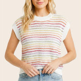 Woman wearing a colorful striped shirt and denim shorts on a plain background
