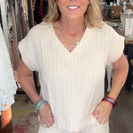 Woman in a white outfit standing in a store with various items in the background