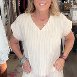 Woman in a white outfit standing in a store with various items in the background